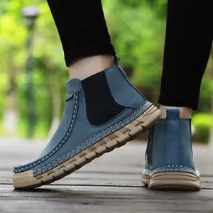 Detail van blauwe suède Chelsea boots met wit contraststiksel en stevige rubberen zolen