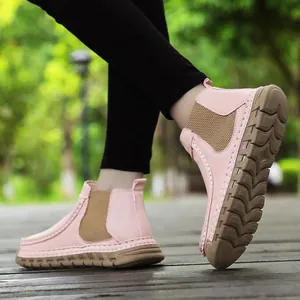 Detail van handgestikte roze suède laarzen met bruin elastiek en antislip rubberen zool