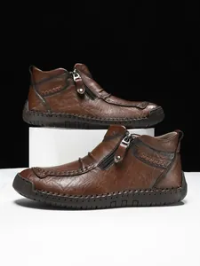 Close-up of brown leather boots showing side zipper and handcrafted stitching detail