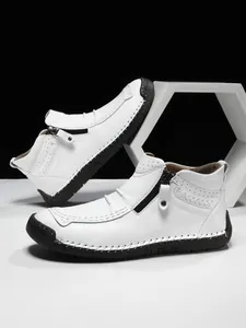 Detail of white leather men boots featuring metal side zipper and contrast hand stitching