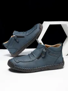 Detail view of men's leather boots featuring side zipper and handmade stitching accents