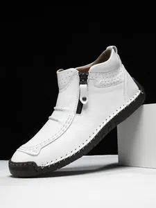 Macro shot of white leather men's boot showing side zipper and hand-stitched details