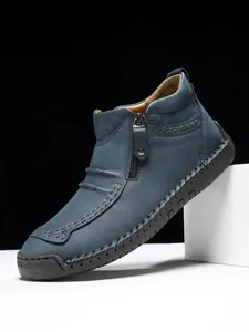 Detail of navy blue suede leather boots showing metal side zipper and moccasin stitching