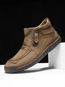 Detail of hand-stitched seams and side zipper on brown leather outdoor boots