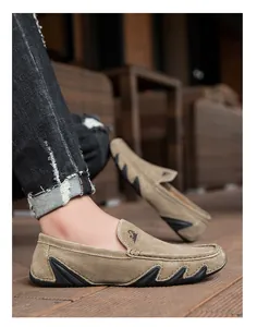 Détail de mocassins en daim kaki avec renforts en caoutchouc et logo animal sur la languette