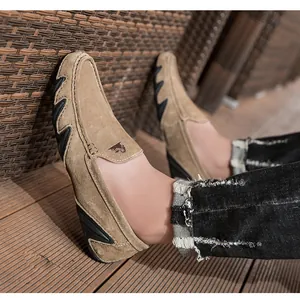 Mocassins en daim kaki avec picots antidérapants et logo bélier sur parquet en bois