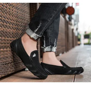 Détail de mocassins en daim noir montrant la semelle en caoutchouc et le logo sur la languette