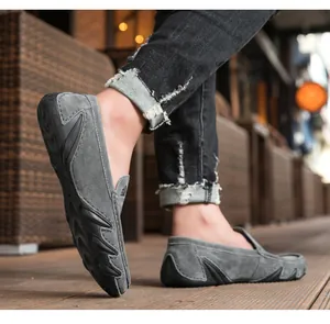 Détail de mocassins en daim gris avec semelle à picots antidérapante sur bois
