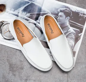 Top view of white leather loafers with contrast stitching on a luxury stone surface
