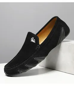 Détail de mocassins en daim noir avec logo mouton argenté et semelle à texture ondulée