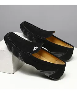 Détail de mocassins en daim noir avec logo bélier blanc et semelle en caoutchouc ondulé