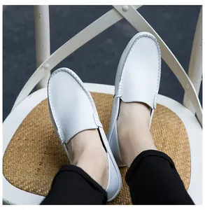 Close-up of white leather loafers showing handmade stitching detail and slip-on design