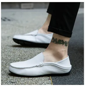 Close-up of white leather loafers with hand-stitched U-shaped toe on a pebble road