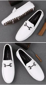 Nahaufnahme weißer Leder-Loafer mit Metallschnalle und brauner Gummi-Noppensohle