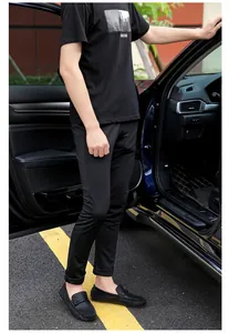 Dettaglio di mocassini da uomo in pelle nera goffrata con pantaloni casual con risvolto