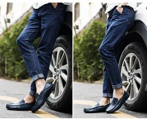 Detail of navy blue leather loafers styled with slim-fit cuffed denim jeans in street setting
