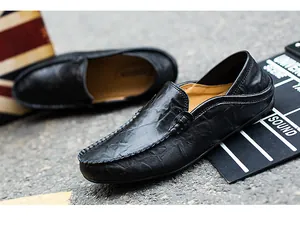Detail view of black leather loafers showing textured grain and hand-stitched toe design