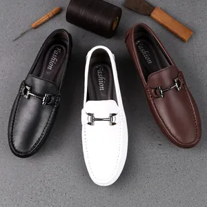 Herren Leder Slipper in Schwarz Weiß und Braun mit Metallschnalle auf grauem Grund