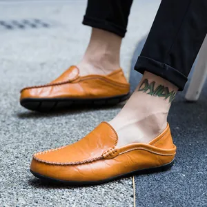 Brown leather loafers for men with handmade stitching on outdoor gravel background