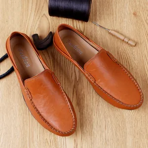 Brown leather loafers for men featuring handcrafted stitching on a wooden surface