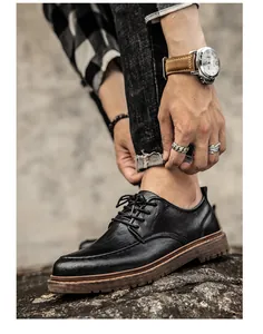 Detalle de zapatos derby de cuero negro con suelas de plataforma robustas y accesorios