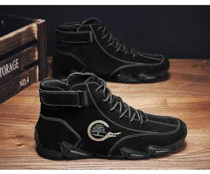 Détail de bottines en daim noir avec surpiqûres contrastées et logo en forme d'arbre