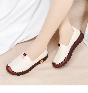Detail view of cream leather loafers featuring a red rubber sole and stylish woven strap