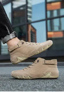 Outdoor shot of khaki high-top casual men's boots with a unique wavy rubber outsole