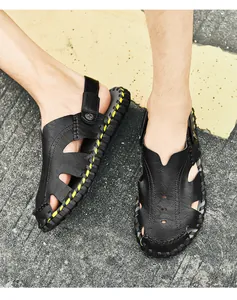 Detalle de sandalias de cuero negro cosidas a mano con costuras amarillas y hebilla metálica