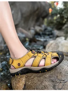 Dettaglio di sandali outdoor in pelle gialla con lacci elastici su rocce naturali di fiume