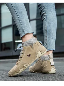 Detail of khaki suede boots with knitted sock collar and non-slip rubber soles outdoors