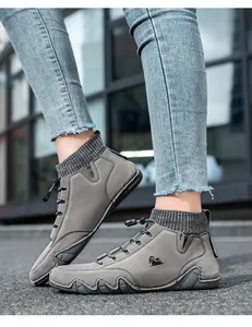 Detail of grey men's sock boots with suede upper and bungee cord laces on asphalt