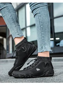 Close-up of black sock-style ankle boots with drawstrings and thick rubber soles