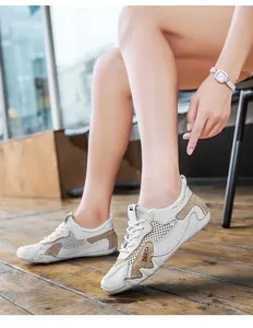 Dettaglio di sneakers in mesh bianco e kaki con cuciture in pelle su pavimento in legno