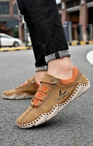 Detail van handgestikte lederen naden en oranje mesh-panelen op casual outdoorschoenen