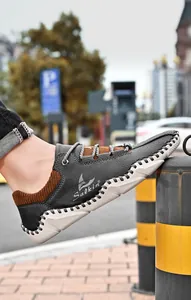 Detail van donkergrijze leren loafers met contraststiksels en een gebreide kraag