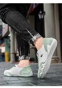 Close-up of low-top sneakers in white and light green leather on urban street