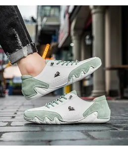 Detailed side view of men's low-top casual leather sneakers with green suede panels