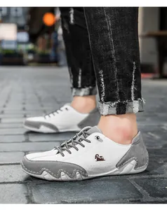 Close-up of low-top sneakers with white leather and grey suede patchwork on outdoor pavement