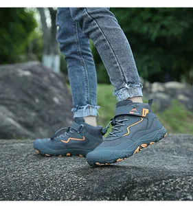 Detail von grauen Outdoor-Kinderschuhen mit orangen Wellen auf felsigem Wanderweg