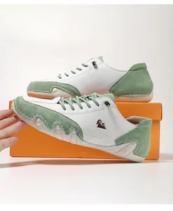 Detail of white and green color-block sneakers with mountain goat logo on wavy sole