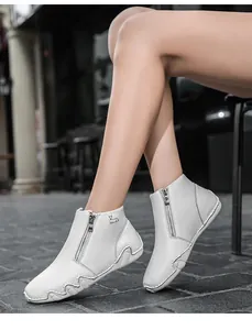 Detail of white leather ankle boots featuring side zipper and non-slip rubber wave sole