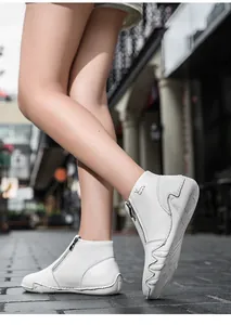 Close-up of white leather boots featuring side metal zippers and textured non-slip soles