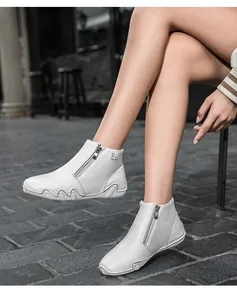 Close-up of white leather boots with deer motif and side zipper on stone floor