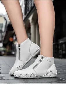 Detail of white leather ankle boots with side zipper and deer logo in outdoor setting