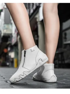 Detail of white leather boots featuring a side zipper and a subtle deer logo on the ankle