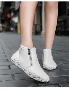 Detail of white leather ankle boots featuring side zipper and minimalist animal logo emblem