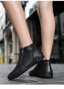 Detail of black leather ankle boot featuring a side zipper and silver deer emblem