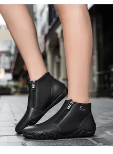 Detail of black leather ankle boots featuring a metal side zipper and embossed deer logo