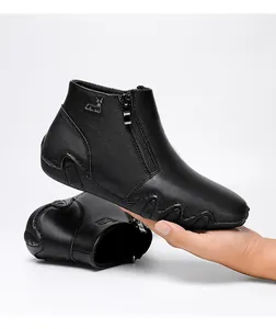 Close-up of black pebble leather ankle boot with silver deer emblem and side zipper